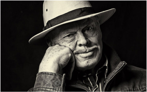 velhote com chapéu mão a descansar na cara